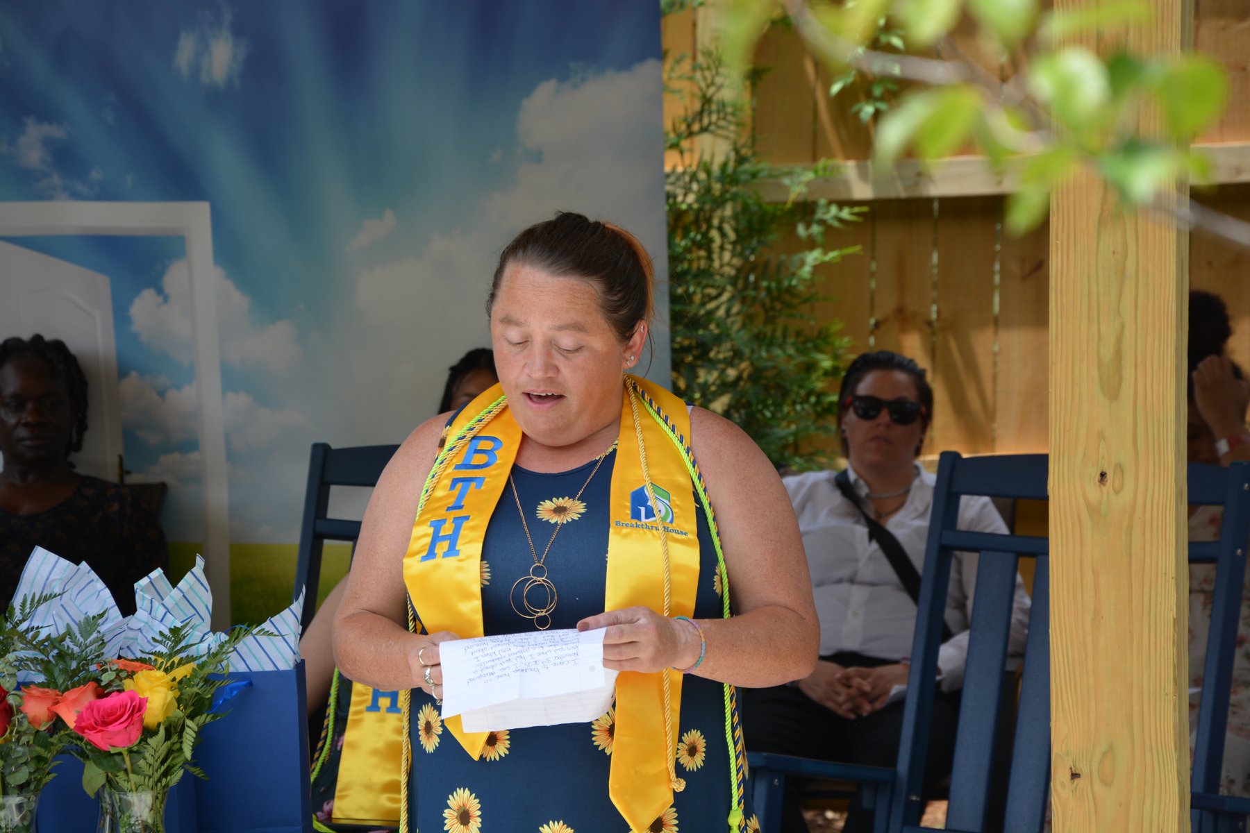 Breakthru House graduate wearing her gold stole and sharing her recovery story